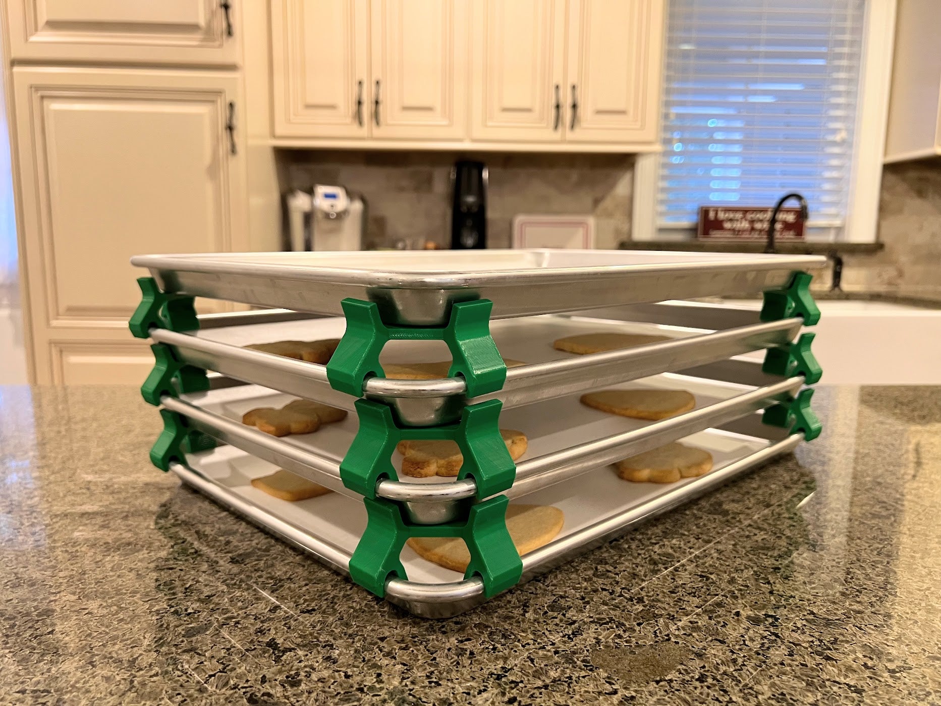 3D printed baking sheet organizers at an angle in green, neatly holding and organizing multiple cookie sheets to save counter space in the kitchen.