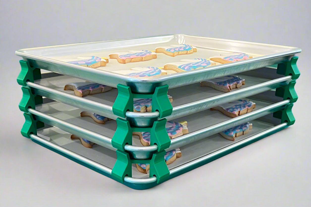 3D printed baking sheet organizers at an angle in green, neatly holding and organizing multiple cookie sheets to save counter space in the kitchen.