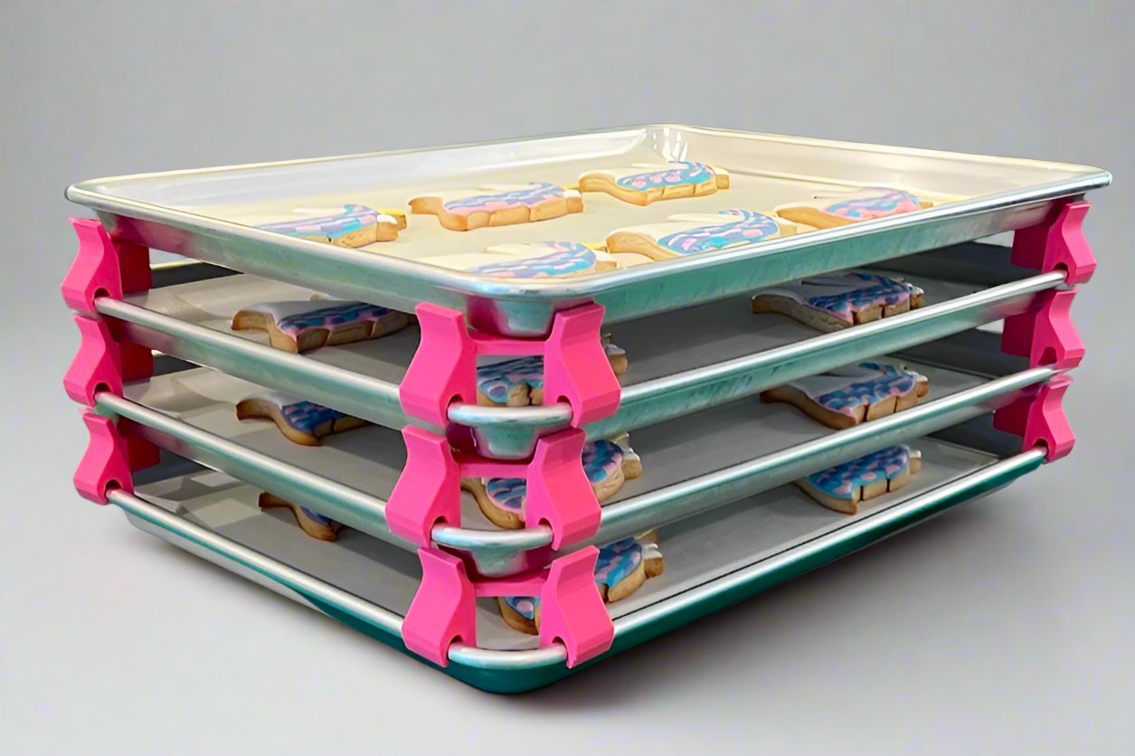 3D printed baking sheet organizers at an angle in hot pink, neatly holding and organizing multiple cookie sheets to save counter space in the kitchen.