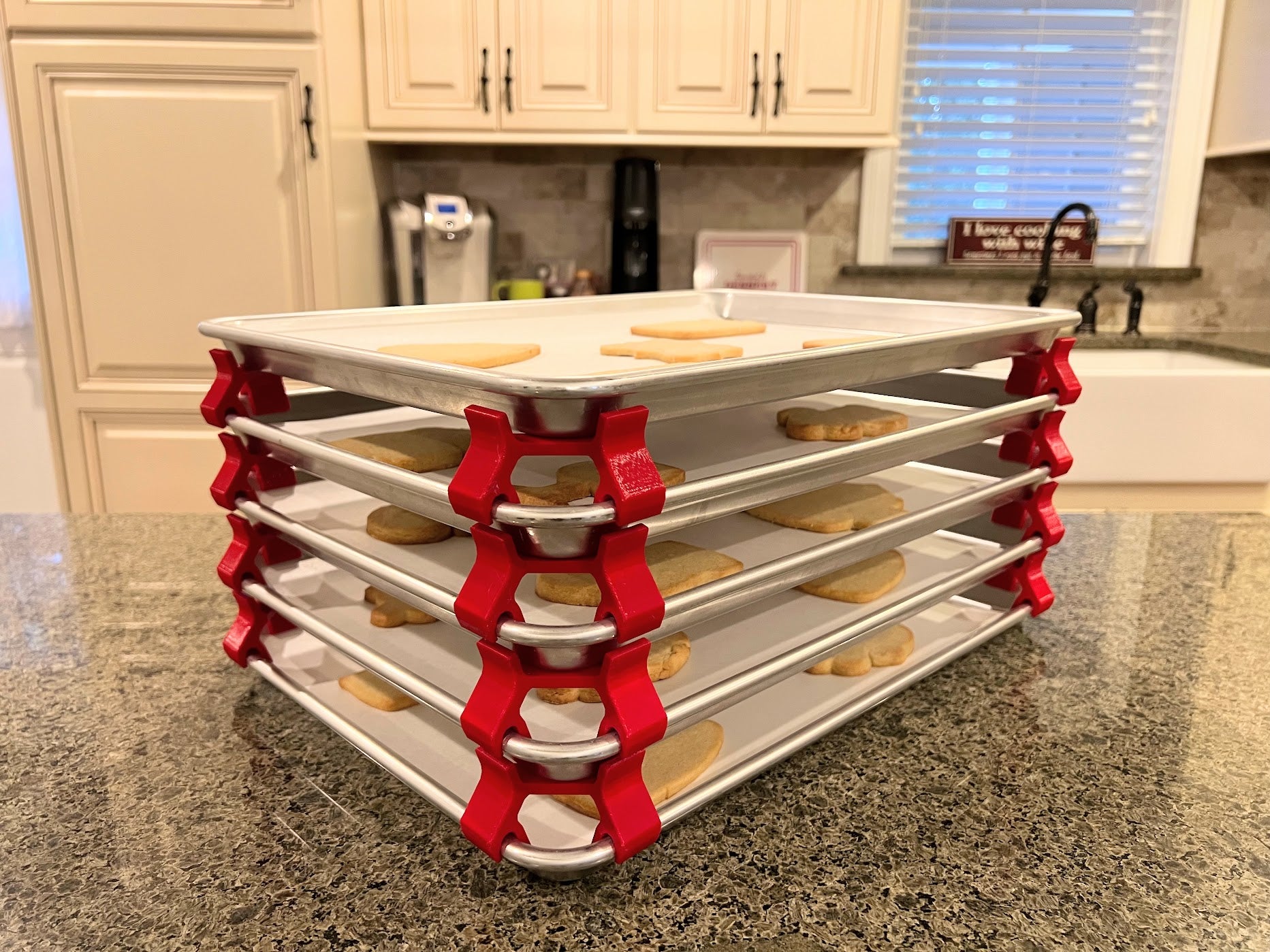 3D printed baking sheet organizers at an angle in red, neatly holding and organizing multiple cookie sheets to save counter space in the kitchen.