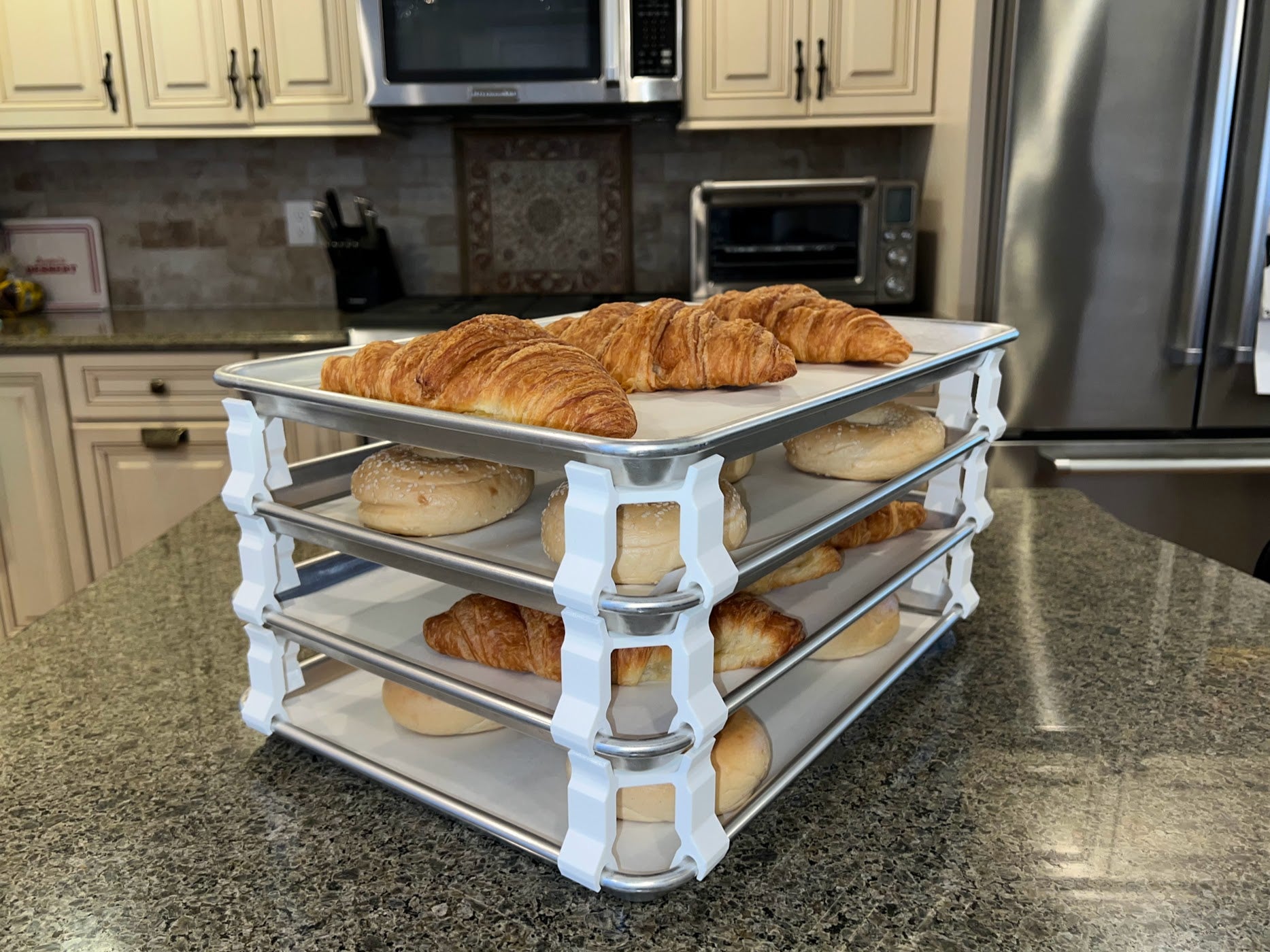 3D printed baking sheet organizers at an angle in white, neatly holding and organizing multiple cookie sheets to save counter space in the kitchen.