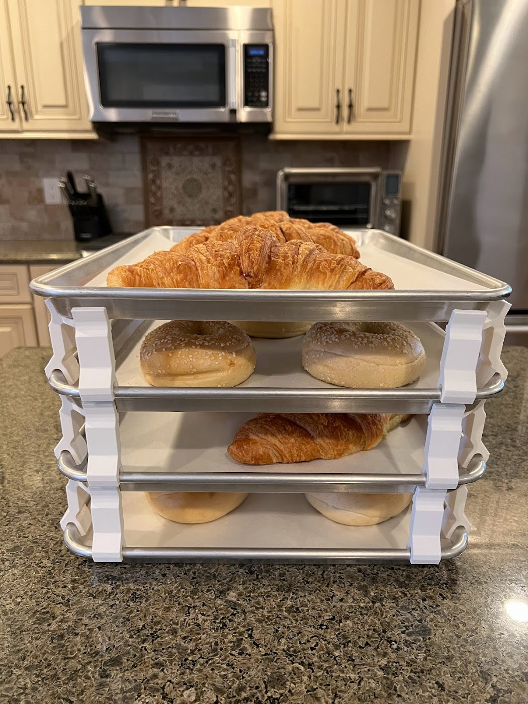 3D printed baking sheet organizers from the front in white, neatly holding and organizing multiple cookie sheets to save counter space in the kitchen.