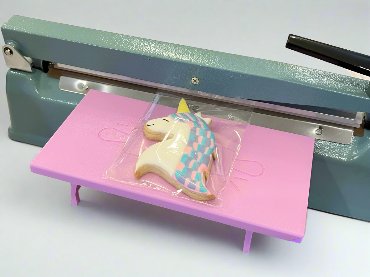 Lavender Heat Sealer Table in the wide position with a unicorn cookie on it.
