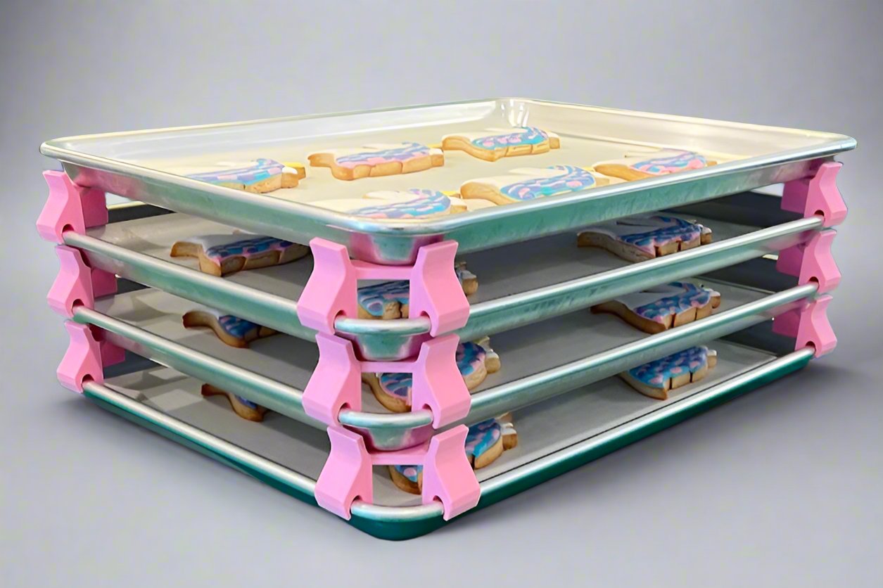 3D printed baking sheet organizers at an angle in pink, neatly holding and organizing multiple cookie sheets to save counter space in the kitchen.