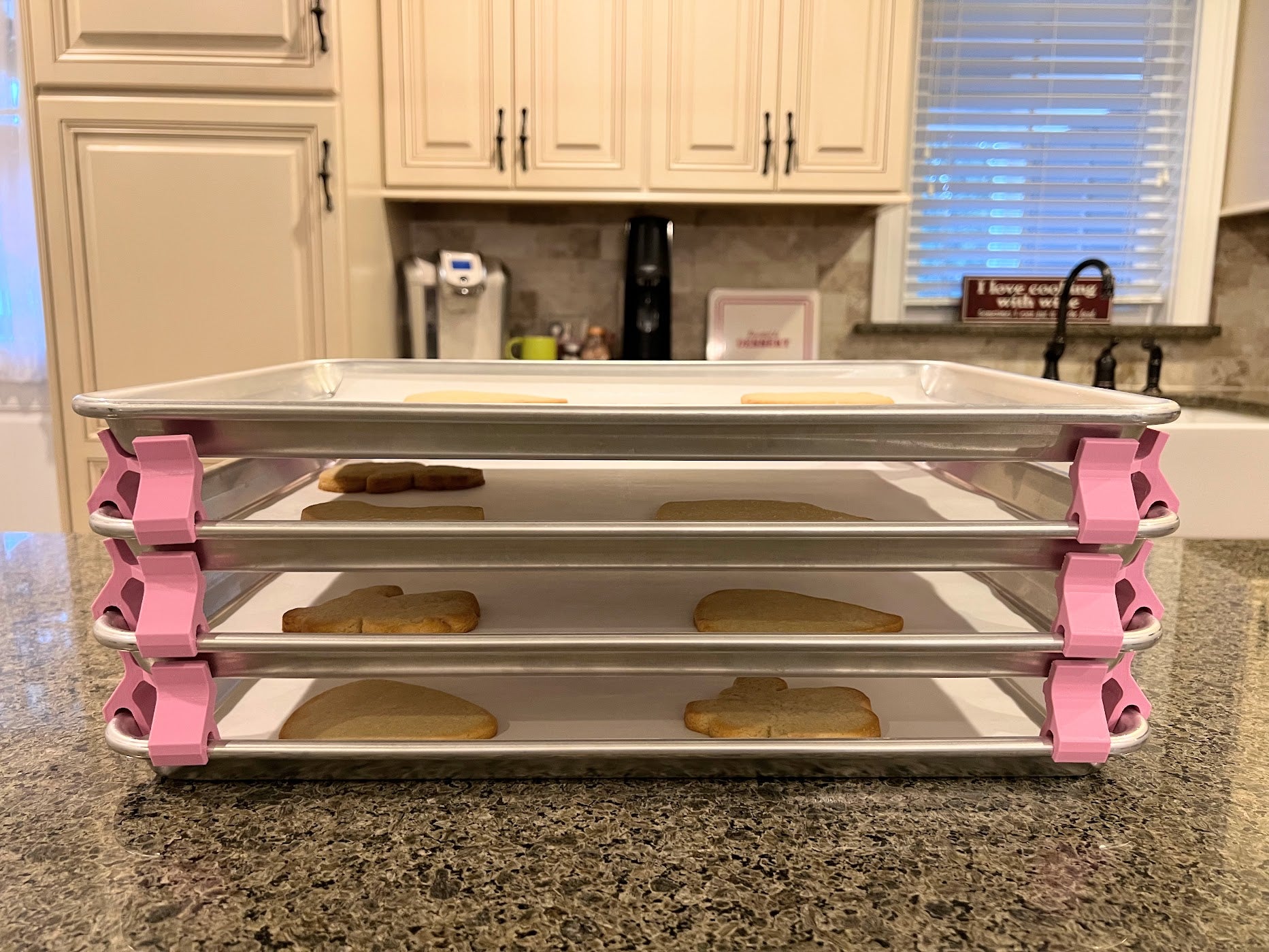 3D printed baking sheet organizers from the side in pink, neatly holding and organizing multiple cookie sheets to save counter space in the kitchen.