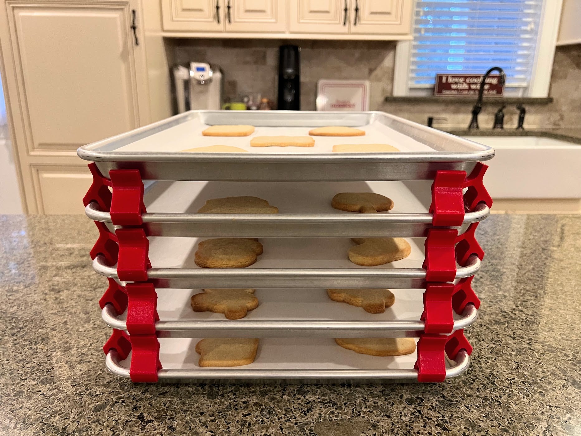 3D printed baking sheet organizers from the front in red, neatly holding and organizing multiple cookie sheets to save counter space in the kitchen.