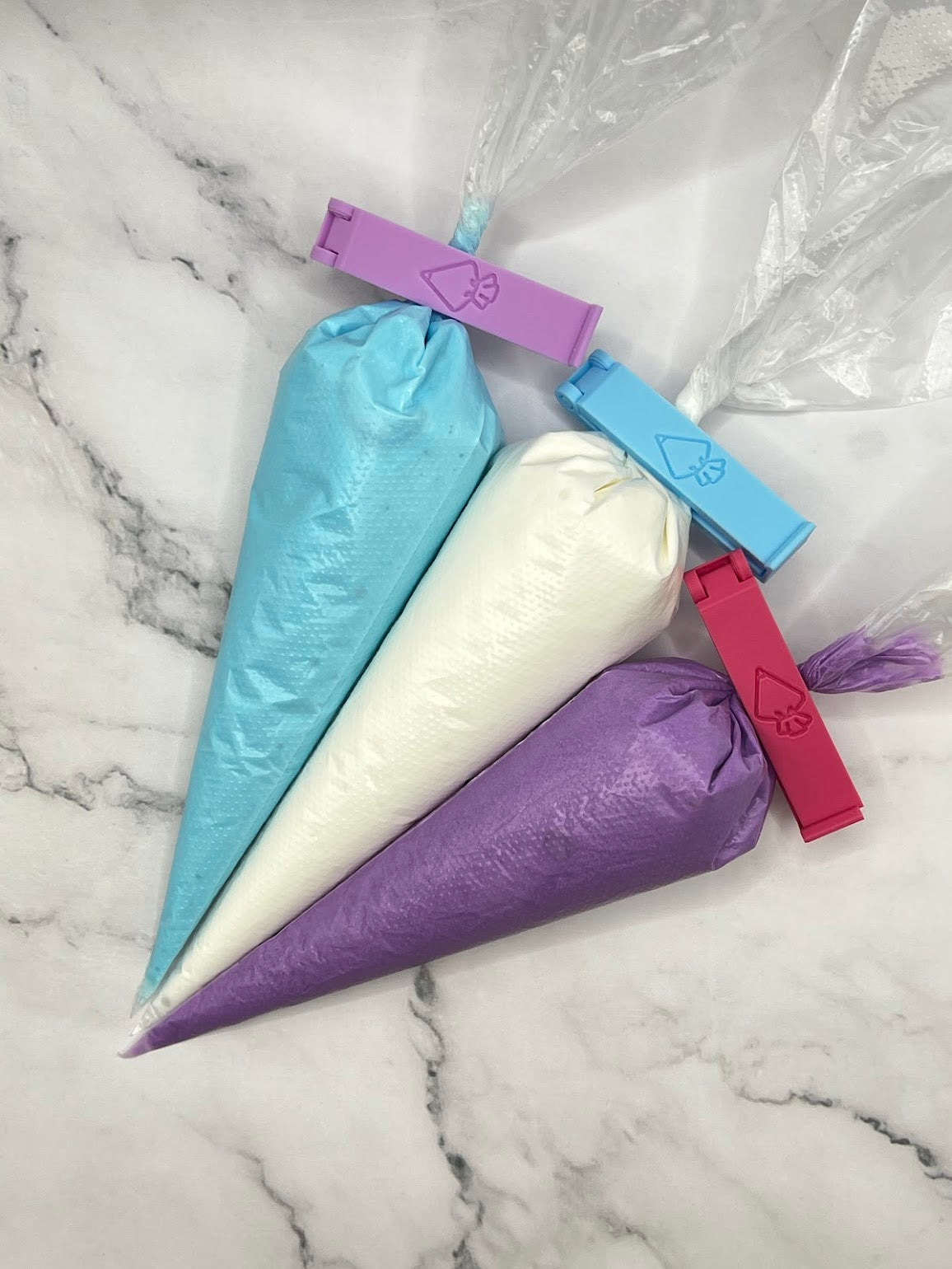 Tipless piping bags with clips on marble counter.